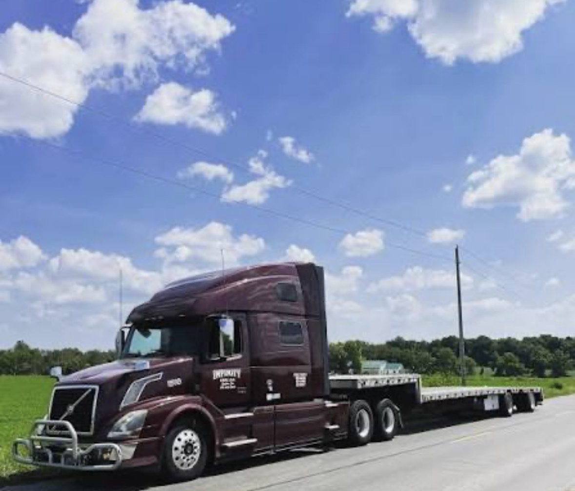 Infinity Line Volvo tractor pulling a step-deck flatbed on a rural highway